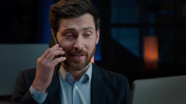 Business consultant office worker employee middle-aged professional businessman 40s man talking mobile phone indoor evening office communicating with client cell connection by smartphone distant talk