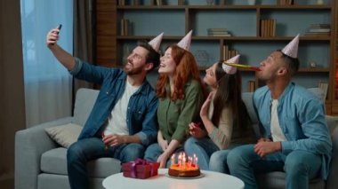 Happy multi ethnic friends diverse men women african american caucasian hispanic people in party hats make selfie photo funny video on mobile phone hold birthday cake celebrate event virtual meeting