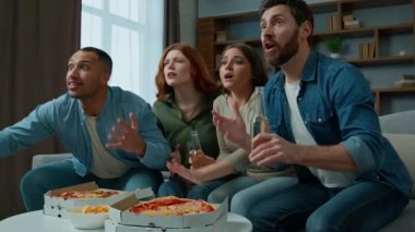 Four friends watch television with beer and pizza at home diverse multiethnic women men sport fans supporters watching tv football match championship soccer game sad worried by team losing bad result