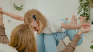 Kafkasyalı anne, gözlüklü bebek bakıcısı oturma odasındaki rahat kanepeye uzanmış, dizleriyle küçük şirin bir kız çocuğu büyütüyor ve evde oyun oynuyor.