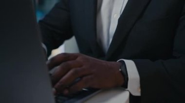 50 'li yılların Afrikalı işadamı içeride bilgisayarla çalışıyor. Kırpılmış görüntüyü kapat. Klavye yazan erkek eller. Ofiste kablosuz bilgisayar.