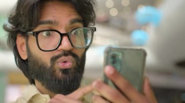 Indian Arabian man in glasses talk to camera of mobile phone online virtual business conversation distant video call. Bearded businessman executive in eyeglasses talking with smartphone conference app