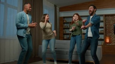Happy friends men women ethnic diversity roommates neighbors have fun together at home party overjoyed multiracial people dancing funny dance move to rhythm music celebrate event in living room indoor