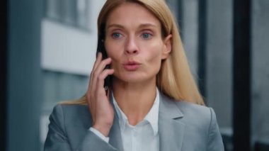 Serious executive confident businesswoman talking mobile phone answering business call caucasian woman professional manager communicate with client remote speaks with partner using cellphone close-up