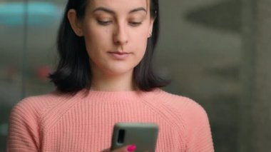 Kafkas kadın 20 'li yaşlarda kapalı bir alışveriş merkezinde kapalı bir alışveriş merkezinde cep telefonuyla mobil ekrana bakarak internet üzerinden akıllı telefon alıyor. İş kadını telefon sohbet sitesine bak