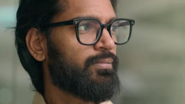Close up pensive thoughtful calm Indian man in eyeglasses spectacles thinking dreaming looking to side. Portrait serious Arabian businessman office company CEO dreamy guy male in glasses look posing