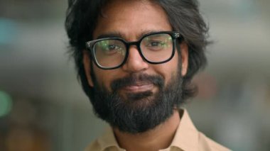 Close up front view Arabic handsome bearded man agent worker guy in glasses Indian company CEO calm businessman in eyeglasses looking at camera posing in office. Male client of ophthalmology service