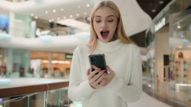 Woman winner use smartphone in business center female shopper shopping online with mobile phone win victory internet discounts new profit excited happy Caucasian businesswoman achieve business success