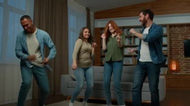 Happy multiracial diverse people four friends ethnic millennial dancers men and women laughing dancing having fun listening music together home party funny moving disco dance celebrating event indoors