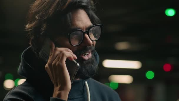 笑顔アラビアの大人の民族男で眼鏡カジュアルなビジネスマンで眼鏡作りビジネスコール電話立って暗い駐車場地下幸せなインドの男性はモバイル会話を楽しむ — ストック動画