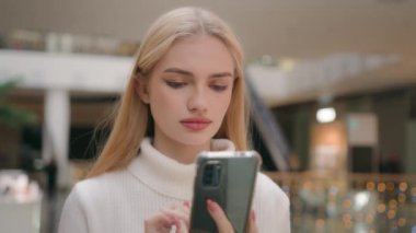 Walking lady look at mobile phone screen in shopping mall Caucasian blonde woman businesswoman shopper going chatting sms online with smartphone make order internet store texting message answer email