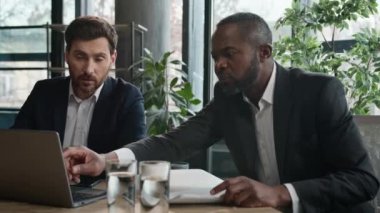 İki farklı şirket çalışanı çok ırklı adamlar iş projesini ofiste tartışıyor. Kafkas ve Afrikalı Amerikalı ortaklar finansal stratejiyi tartışıyor şirket geliştirme sonuçları dizüstü bilgisayarla