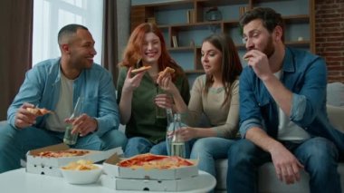 Arkadaşlar Etnik Kafkas Afrikalı Amerikalı kadınlar ve erkekler evde kutlama masasında kutlama yapıyorlar. Çok ırklı pizzalar yiyorlar. Eğlenceli takılma partileri, kurumsal öğle yemeği.
