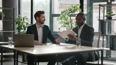 Multiethnic Caucasian and African American business people diverse men two male partners at office desk sign document shake hand signing corporate paper contract handshaking successful partnership