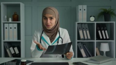 Muslim doctor woman radiologist talking with patient distant use video app explain MRI tomography result show x-ray image make virtual medical checkup online treatment say good diagnose webcam view