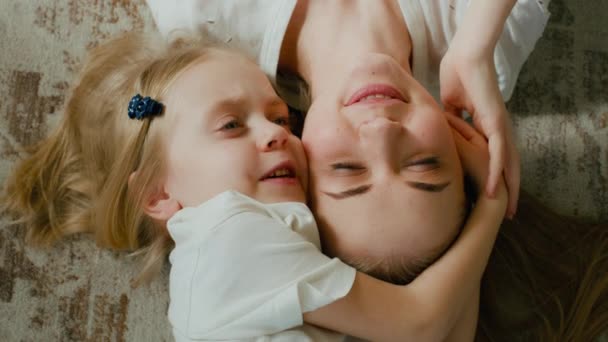可爱的情意收养了幼儿学龄前女孩抱着拥抱妈妈的头顶视图 孩子的女儿 两个脸蛋抱在怀里躺在家里 微笑着 紧闭着温柔的眼睛 — 图库视频影像
