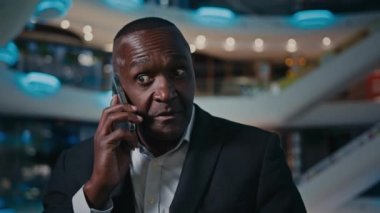 Orta yaşlı Afrikalı girişimci etnik adam ev içi aramalara cevap veriyor. Cep telefonuyla gelen iyi haberleri dinle. Şok edici duygular.