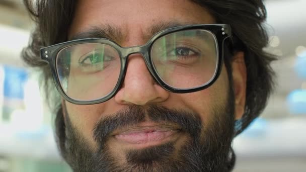 用眼镜把阳性男性的脸闭上 照片上的印度大胡子男人戴着眼镜 微笑着看着相机 头像企业家家伙商人行政室内与灯光反射镜 — 图库视频影像