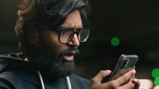 不幸なアラビア人男性メガネ男でインドのビジネスマンは スマートフォンを使用していらいらを感じる 怒っている男性は駐車場でバッテリー不良信号が少ないことに不満を持つ携帯電話のスパムメッセージユーザーに問題があります — ストック動画
