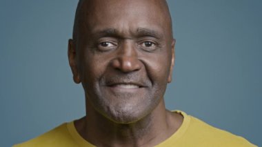 Male portrait mature african american man looking camera smiling with white toothy smile joyful ethnic senior male athlete satisfied client happy with service laughing posing in blue background studio