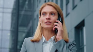 Açık havada cep telefonuyla konuşan kendine güvenen bir iş kadını başarılı bir genç kadın girişimci iş ortağı olan bayan yöneticiyle cep telefonuyla iletişim kuruyor.