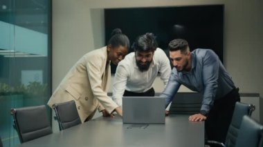 Diverse business people multiracial corporate group project team African woman and Indian Arabian men win success online good result with laptop happy stack hands put palms together united celebrate