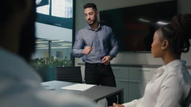 Arabian Indian company CEO man leader businessman executive talking to diverse business team male worker and African American woman talk about ideas with paper documents project presentation in office