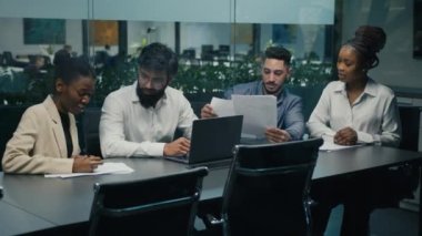 Creative diverse multiracial professional multiethnic business team partners workers colleagues working together discussing project ideas with laptop and documents at office meeting brainstorming