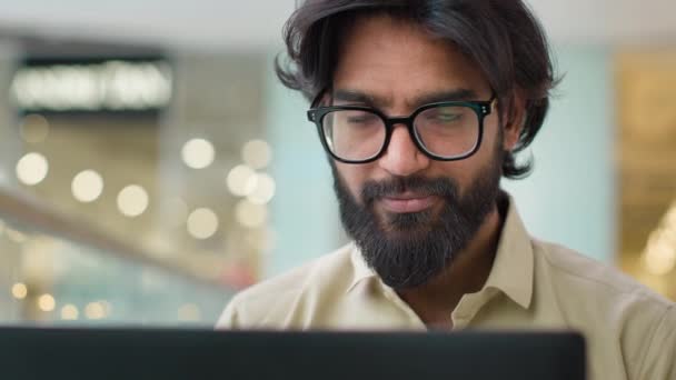 Индиец Очках Смотрит Экран Ноутбука Работающий Помещении Улыбаясь Камеру Закрыть — стоковое видео