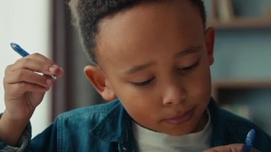 Concentrated smart African American schoolboy Latin preteen school boy pupil child studying lesson writing with pen. Serious kid primary class student write exercise homework home learning education