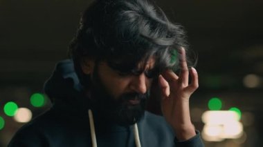 Close up sick ill sad Arabian man unhealthy Indian guy at parking lot headache bearded male suffer from migraine pain brain cancer symptom tumor high blood pressure injury massage temple painful head