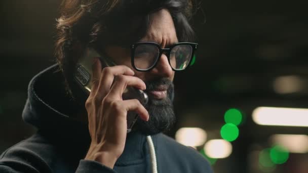 インドの髭は 暗い駐車場の暗闇の背景で スマートフォンで悪いニュースを聞いている深刻な男性を強調しました アラビア人男性社員電話ストレス会話ビジネスの失敗 — ストック動画