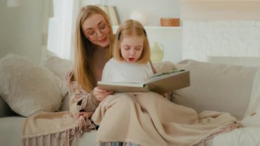 Bekar bir ebeveyn, beyaz bir anne, bebek bakıcısı, ana kuzusu, battaniyeye sarılmış küçük bir kız çocuğu, kanepeye oturup kitap okumayı, aile eğitimini evde birleştirmeyi öğreniyor.