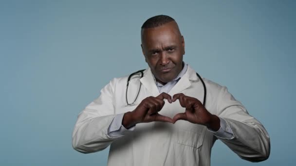 Dojrzałe Uśmiechnięty Afryki Człowiek Lekarz Kardiolog Biały Płaszcz Stoisko Niebieskim — Wideo stockowe