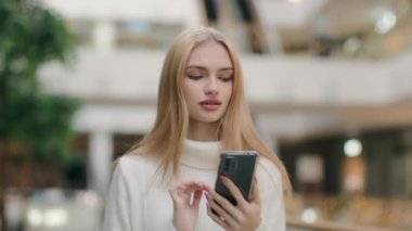 Elegant blonde woman businesswoman model walking in business mall shopping online use smartphone app make order Caucasian girl female going with mobile phone texting message searching internet website