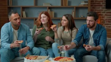 Çeşitli insanlar evde şenlik partisinde bira şişeleriyle otururlar. Yetişkin, etnik, çok ırklı arkadaşlar alkol içen kadınlar ve erkekler pizza dağıtımı yapıyorlar, akşam yemeklerini birlikte yiyorlar, evde sohbet ediyorlar.