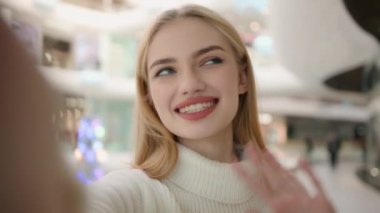 Webcam view blogger Caucasian woman lady shopper blonde girl record blog in shopping mall online video streaming for social media looking at mobile phone selfie camera speaking talking trend blogging