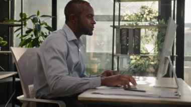 Mutlu Afrikalı Amerikalı olgun 40 'lı yaşlarda orta yaşlı iş adamı güneşli ofis ışıklarının arkasında oturuyor bilgisayardan online piyango kazanıyor zaferi kutluyor iş başarısı iyi sonuç