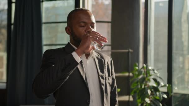 アフリカ系アメリカ人成熟した実業家シニア男性起業家熱い太陽の輝くオフィスで純粋な液体の水ガラスを飲む喉の渇き冷たい水和ボディケア健康リフレッシュを飲む感じ — ストック動画