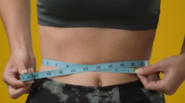 Karın bölgesindeki kadın vücudunu kapatın. Karın bölgesinden, tanınmayan bir spor kadını. Bel ölçüsü, bilinmeyen sporcu, zayıf bayan, vücut zayıflığı, kilo kaybı kalorileri, vücut gelişimini kontrol ediyor.