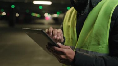 Closeup male hands hold digital tablet unknown man builder in safety uniform unrecognizable industry engineer male industrial specialist factory worker in yellow vest typing browsing online inspection