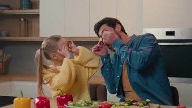 Kafkasyalı komik bir kız çocuğu ve mutfakta yetişkin bir babası var. Salatalık dilimleri yapıyor. Sebze halkaları takan gözlük takıyor.