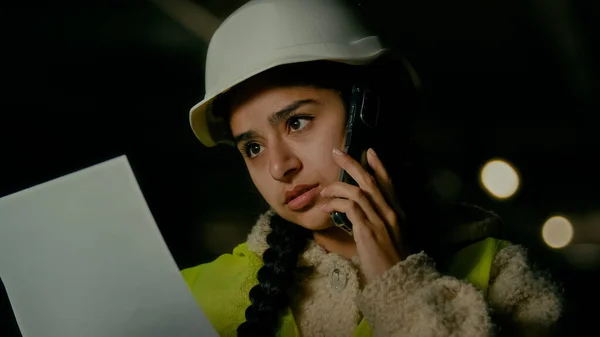Arabian woman technical engineer female architect businesswoman contractor inspector chief in uniform helmet talk mobile phone discuss business contract plan of construction control engineering work