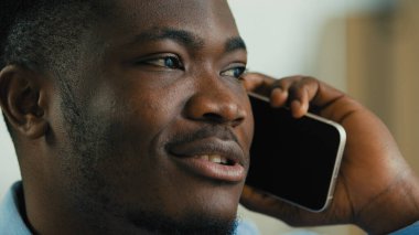 Close up african american man talking phone indoors ethnic smiling male 30s businessman speak with mobile smartphone call negotiate professional office worker entrepreneur manager communicating remote