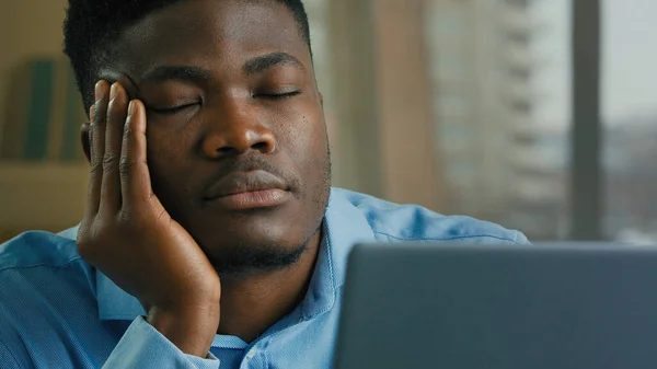 Sleepy overworked tired african american man employee manager businessman fall asleep at office desk sleeping napping exhausted guy resting with eyes closed feeling exhaustion lack of sleep after work