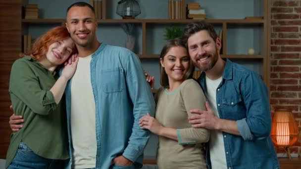 客厅里的多种族人士四个微笑的朋友男女搭档站在家里不同种族的男人女孩队友拥抱室内友谊的概念 — 图库视频影像