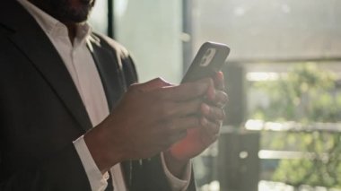 Close up male hands use phone cellphone mobile app mature African American man businessman stand in sunlight in office adult winner win finance bet online lottery on smartphone triumph victory prize