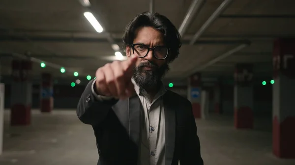 Close-up serious Indian man HR manager choosing candidate for job point finger at camera making inviting come here beckoning gesture ethnic young businessman standing in underground parking welcoming