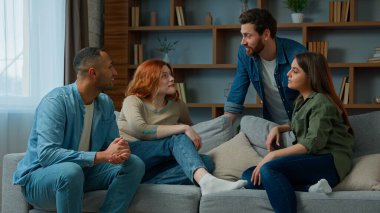 Group friends ethnic diverse women and men multiracial companions business people sit on sofa discuss plans talk indoors approve cooperation stacking hands together in pile team gesture unity teamwork