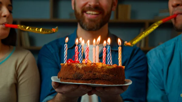 Cropped view caucasian adult happy bearded man celebrate birthday at home diverse african caucasian friends congratulate male with festive cake blowing party whistles make surprise annual tradition